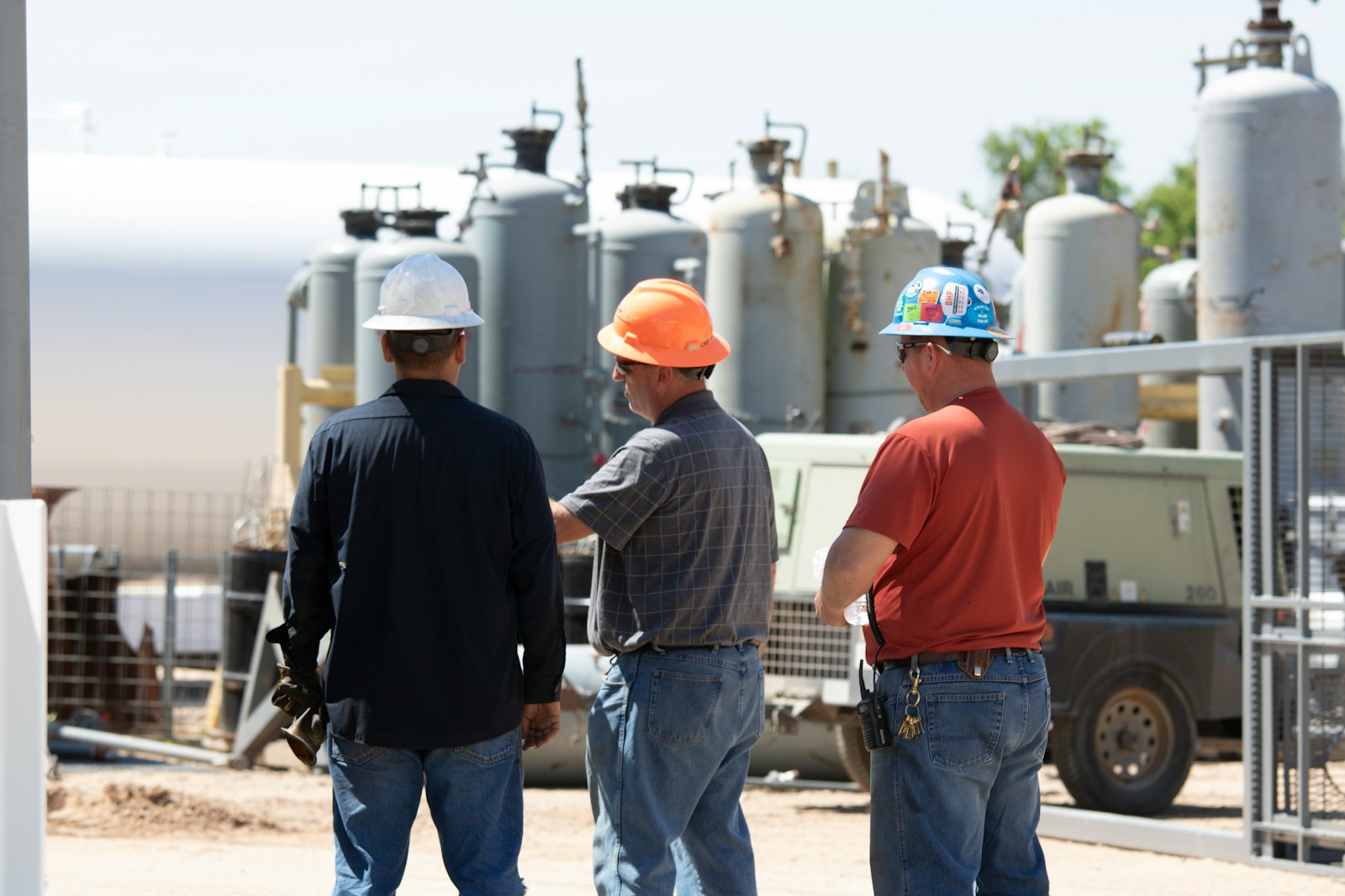 man in black jacket standing beside man in orange shirt, workers' compensation